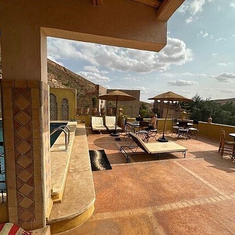 Blick auf Terrasse mit Pool und Sonnenliegen