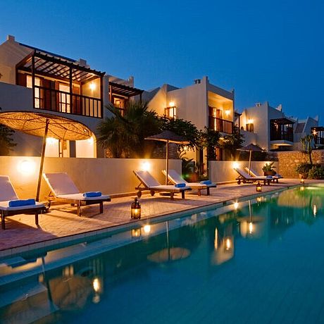 Pool mit Abendbeleuchung und Villas im Hintergrund