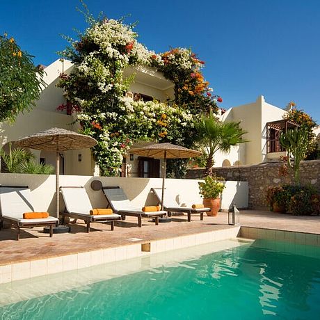 Pool mit Sonnenliegen und Bougainvilla-bewachsener Villa
