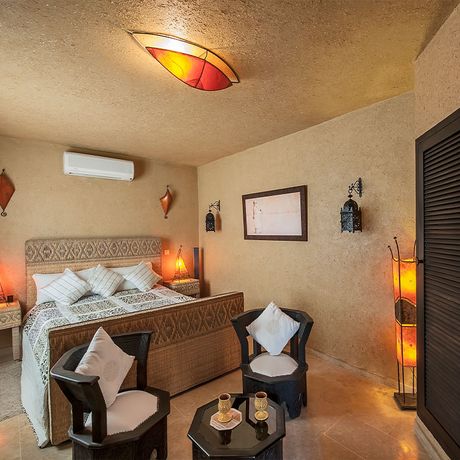 Blick auf ein Bett und zwei Sessel an einem Tisch im Schlafbereich des Standardzimmers Savane Terrasse