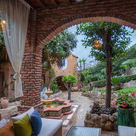 Blick auf einen Sitzbereich und einen Springbrunnen am Garten des Hotels Dar Echchaouen