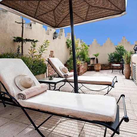 Blick auf zwei Liegen unter einem Sonnenschirm auf der Terrasse des Riads Soleil d´Orient